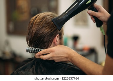 Master cuts hair and beard of men in the barbershop and uses a hair dryer - Powered by Shutterstock