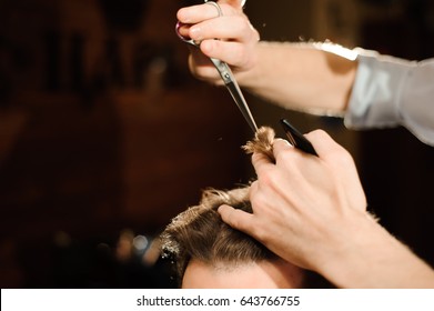 Master cuts hair and beard of men in the barbershop, hairdresser makes hairstyle for a young man - Shutterstock ID 643766755