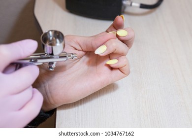 The master does the design on the nails with an airbrush.