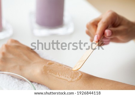 Master does epilation of hands with help of sugar paste hot wax in salon beauty