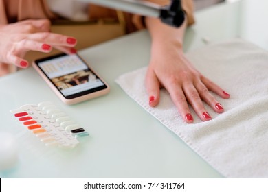 The Master Does A Manicure To A Girl, A Red Nail Polish, She Looks Into The Phone