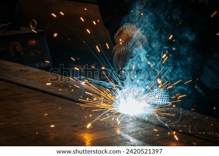 Master is doing welding at his workplace in the workshop, while 