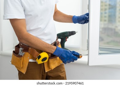 Master in gloves adjusting pvc windows with screwdriver closeup. Installation of plastic windows repair and maintenance concept. - Shutterstock ID 2195907461