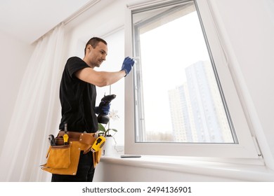 Master in gloves adjusting pvc windows with screwdriver closeup. Installation of plastic windows repair and maintenance concept - Powered by Shutterstock