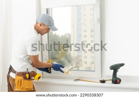 Master in gloves adjusting pvc windows with screwdriver closeup. Installation of plastic windows repair and maintenance concept.