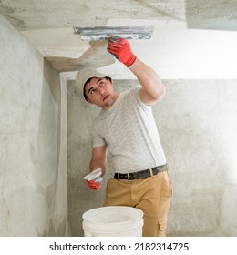 The Master In Gloves Aligns The Ceiling With Lime Plaster Close Up.