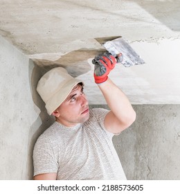 The master in gloves evens out the ceiling with lime plaster close up, repairing the room with his own hands. - Shutterstock ID 2188573605