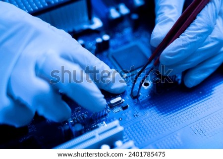 a  computer master in gloves working with tweezers on   cpu board