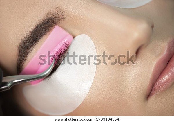 Master glues eyelashes to pink lash roller.\
Close-up of beauty model\'s face during lash lift laminating botox\
procedure. Eyelash Care Treatment: lifting and curling, lash\
lamination and\
extension.