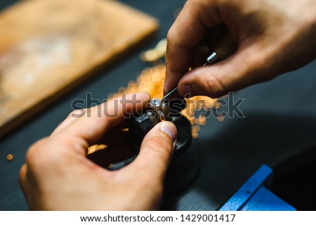 Master goldsmith while working on jewelry on the of work table.