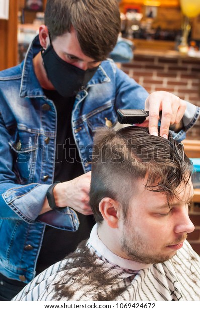 Master hairdresser\
cuts a man in the salon