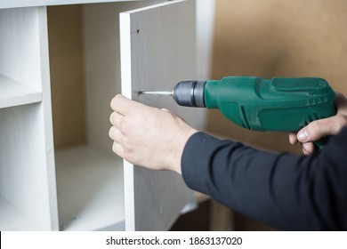 The Master Holds A Puncher In His Hands And Drills A Hole. Power Tool Rental Concept. Manufacture Of Cabinet Furniture