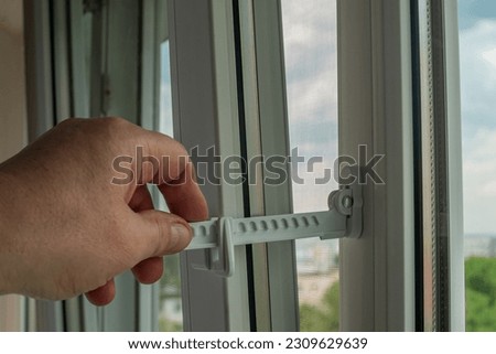 Master installed fixing limiter for opening a plastic window and checks its operation. Close-up of a hand checking the operation of window fittings. Home repairs. Installing window hardware.