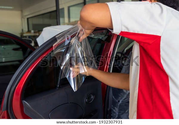 master installs a tint film for\
the car glass with soft-focus and over light in the\
background