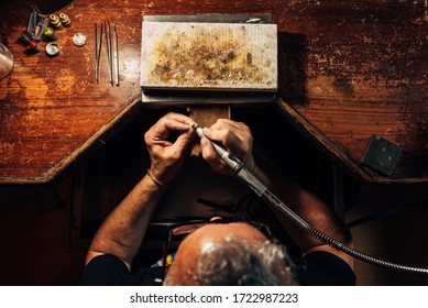 Master jewelry craftsman performs his trade at his desk in the workshop. View from above of a worker at his workplace. - Powered by Shutterstock