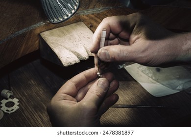 master of jewelry manually inserts gems into the frame of future jewelry. Working desk for craft jewelry making with professional tools. Sapphire diamond ring on the jeweler's desktop - Powered by Shutterstock