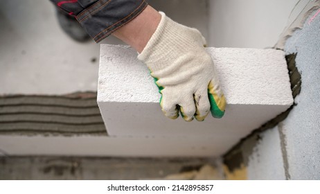 The master lays a wall of blocks. Builder builds a concrete wall made of cement blocks on the construction site of a residential building with his own hands. Concept of building a house. 