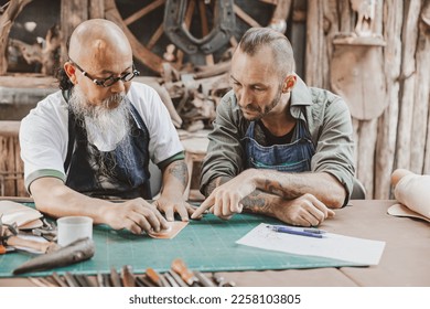 master of leather tailor teaching and training young man for making handcraft leather pouch