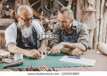 master of leather tailor teaching and training young man for making handcraft leather pouch