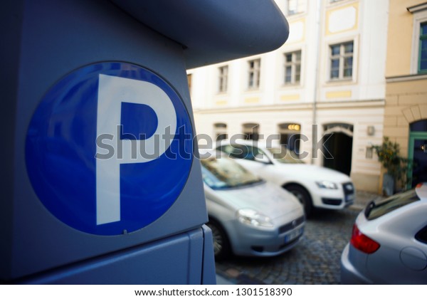 Master meter ticket machine for vehicle parking.\
Luxurious car searching for parking in noble European city\
environment with classic houses background bouquet driving on paved\
road. Blue \