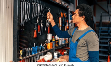 A master in overalls puts tools on the wall, which is very organized - Powered by Shutterstock