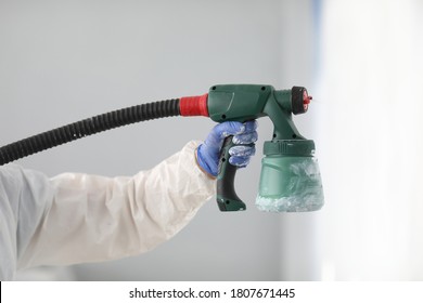 Master Paint Wall With White Paint. Male Hand In Protective Suit Hold Spray Gun In His Hand Close Up.