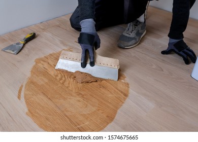 Master Parquet With Spatula In Your Hand. Preparation Of Parquet Grout Material. Mixing Retainer, Varnish And A Small Mixture Of Wood. Pre-varnishing Phase