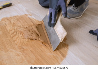 Master Parquet With Spatula In Your Hand. Preparation Of Parquet Grout Material. Mixing Retainer, Varnish And A Small Mixture Of Wood. Pre-varnishing Phase