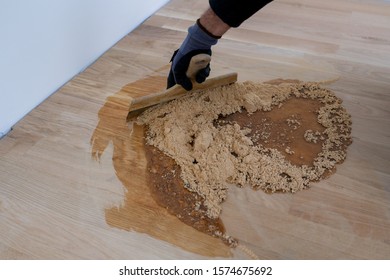 Master Parquet With Spatula In Your Hand. Preparation Of Parquet Grout Material. Mixing Retainer, Varnish And A Small Mixture Of Wood. Pre-varnishing Phase