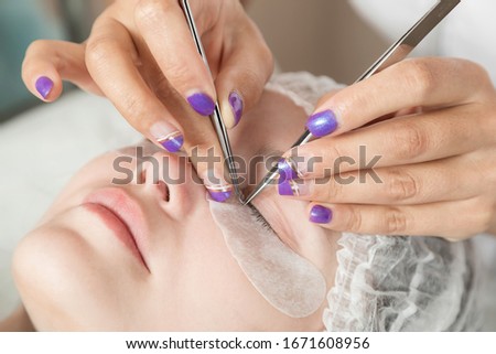 master is performing procedure of lash extension on female eyelids
