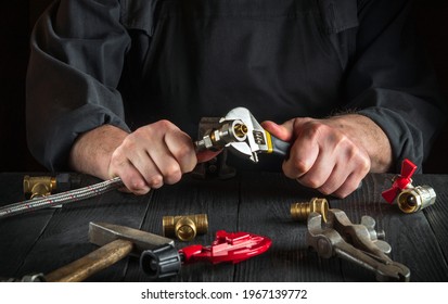 Master plumber connects the brass fittings to the faucet with an adjustable wrench. Close-up of a foreman is hands while working in a workshop - Shutterstock ID 1967139772