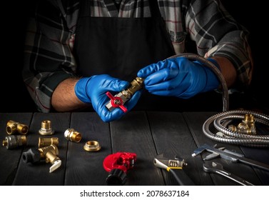 Master plumber connects brass fittings when repairing equipment or installing gas. Close up of gloved hands of foreman while working in workshop.
