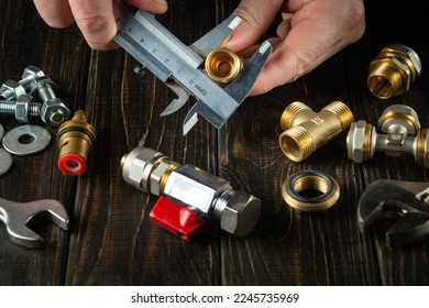 Master plumber measures the diameter of a fitting with a caliper. Working environment in the workshop when connecting gas equipment.