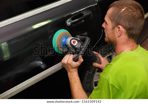 The master polishes the car with a grinder with\
paste. Car care.