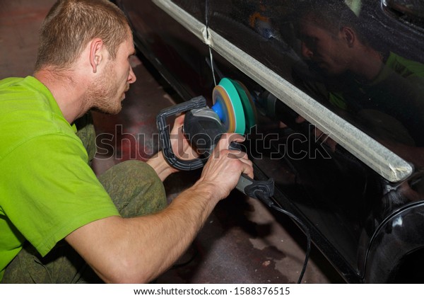 The master polishes the car with a grinder with\
paste. Car care.