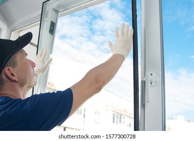 master in protective gloves  changing double  glazed window in plastic window  side view  against the blue sky