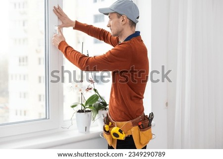master in protective gloves, changing a double-glazed window in a plastic window.