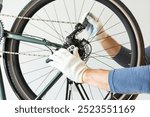 Master in protective gloves tightens the bolts on the bicycle system of a sports bike with a hex wrench. Professional repair and service of sports bikes