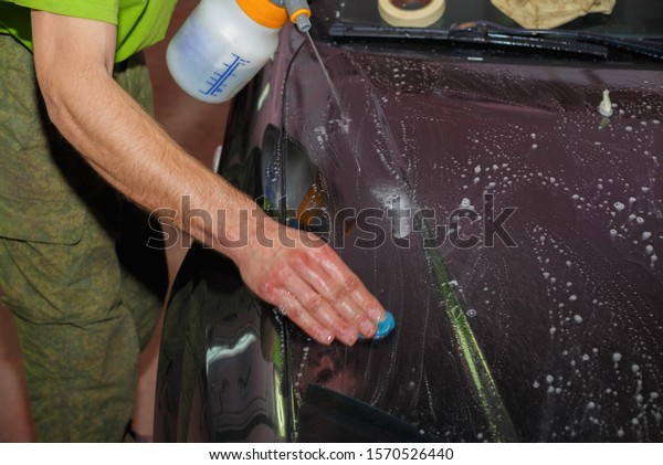 The master removes dirt from the car\
with special clay before polishing. Car\
care.