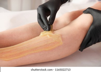 Master removes hair on legs with sugar paste. Concept epilation.