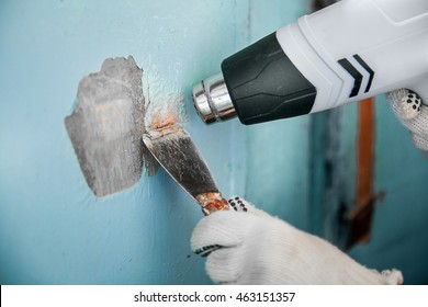 Master Removes Old Paint From Concrete Wall With Heat Gun And Scraper. Closeup