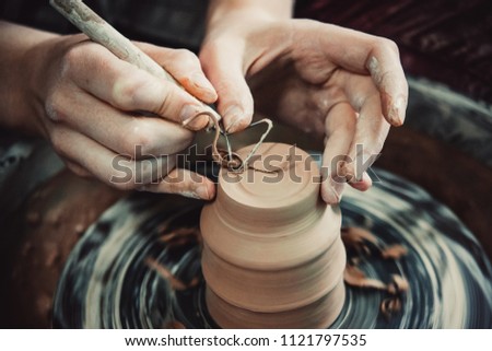 Master removes the top layer of clay on pot with a special tool. Create clay vessel. Modeling white-clay, shaping vessel. Caucasian man making vessel. Clay in circle.