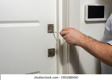 master repairing a door lock in a room, a man fixing a lock with a screwdriver, Close-up of a door repair