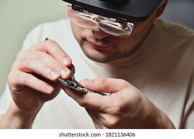 Reparador maestro de equipo electrónico utiliza vidrio de lupa óptica binocular en el trabajo