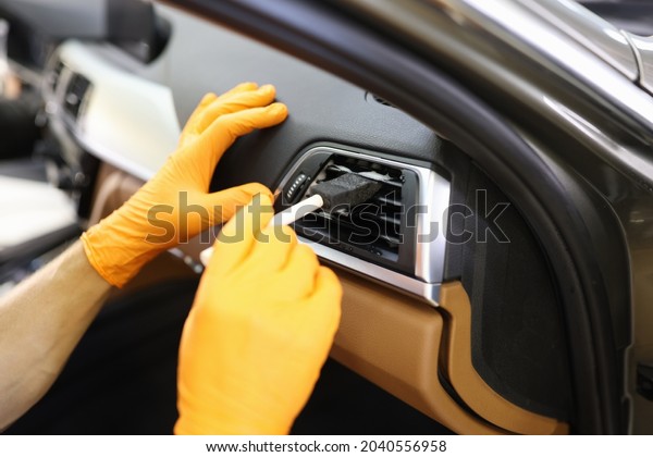 Master repairman in rubber gloves\
cleaning car air conditioner with brush in workshop\
closeup