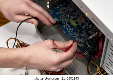 the master repairs the computer measures the voltage on the board with a multimeter. High quality photo
