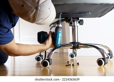 Master repairs office chair with a screwdriver. - Powered by Shutterstock