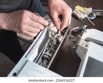 Master repairs the sewing machine. Internal cleaning of the mechanism. Professional adjustment of a sewing machine in a small factory. Cleaning and repair of professional equipment.