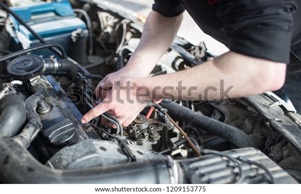 The master\
repairs under the hood of the\
car