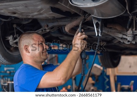 Master replacing of  muffler of exhaust system in car workshop. Car exhaust system repair.
